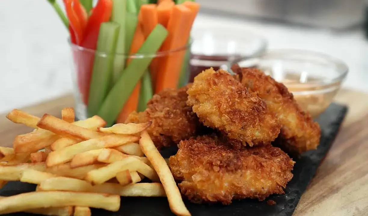 Krispiga chicken nuggets med pommes frites och grönsaksstavar. Perfekt för en mysig kväll!