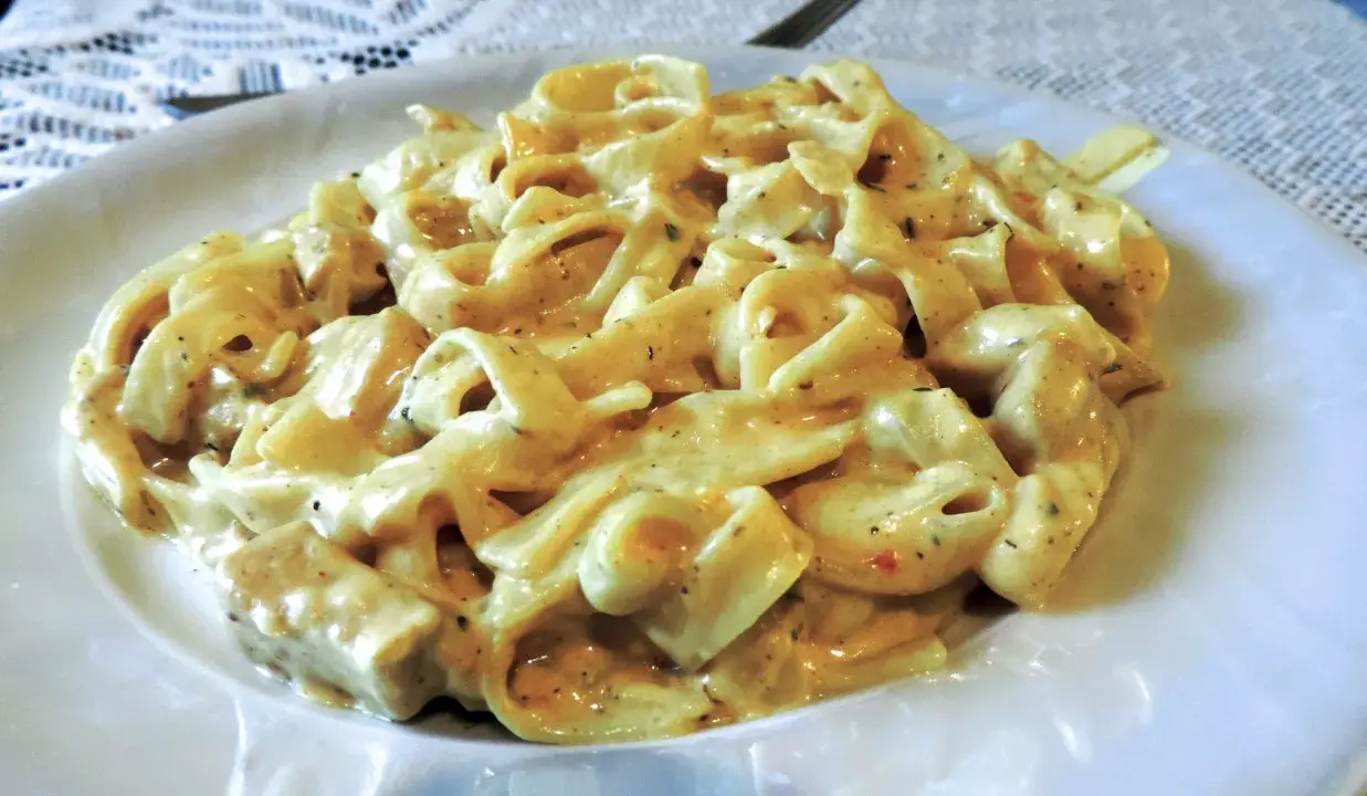 Pyszne tagliatelle z kurczakiem w kremowym sosie, podane na białym talerzu.