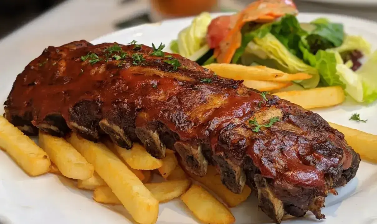 Soczyste żeberka w sosie BBQ, podane z chrupiącymi frytkami i świeżą sałatką. Idealna marynata do żeberek sprawia, że mięso jest niezwykle aromatyczne.