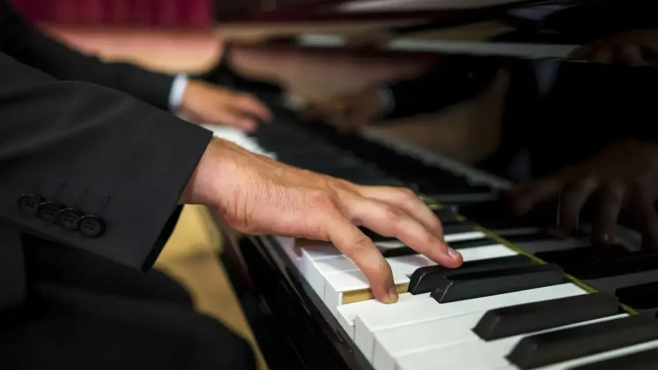 Dłoń muzyka w garniturze gra na fortepianie. Zastanawiasz się, ile bierze organista za ślub?