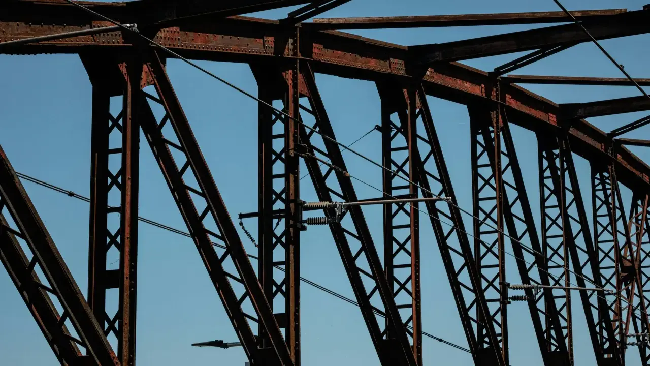 Estructura de puentes de hierro famosos contra el cielo azul. Cables cruzan la intrincada red de vigas oxidadas.