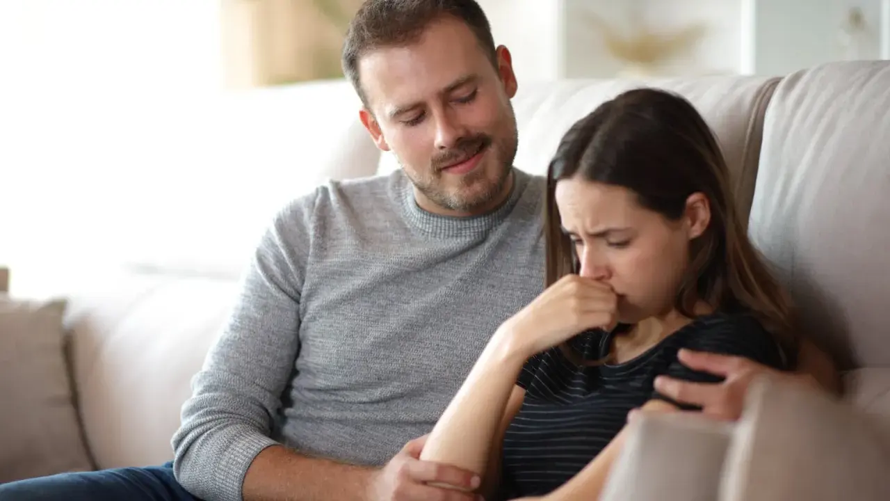 Un homme réconforte une femme en pleurs, son regard suggère une manipulation subtile, un exemple de pervers narcissique.