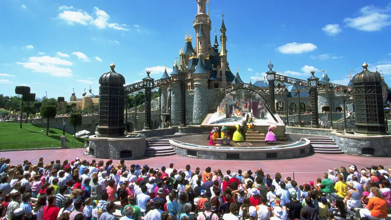 Disneyland Paris con niños: un espectáculo de princesas frente al castillo, con una multitud emocionada disfrutando del día.