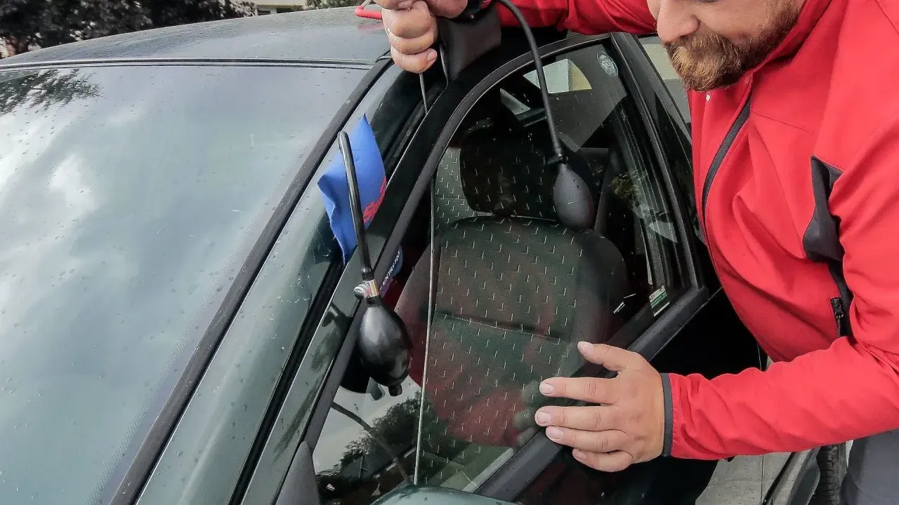 Mężczyzna używa pompki i narzędzia do otwierania drzwi, gdy zatrzasnął kluczyki w samochodzie. Jak otworzyć auto bez kluczyka?