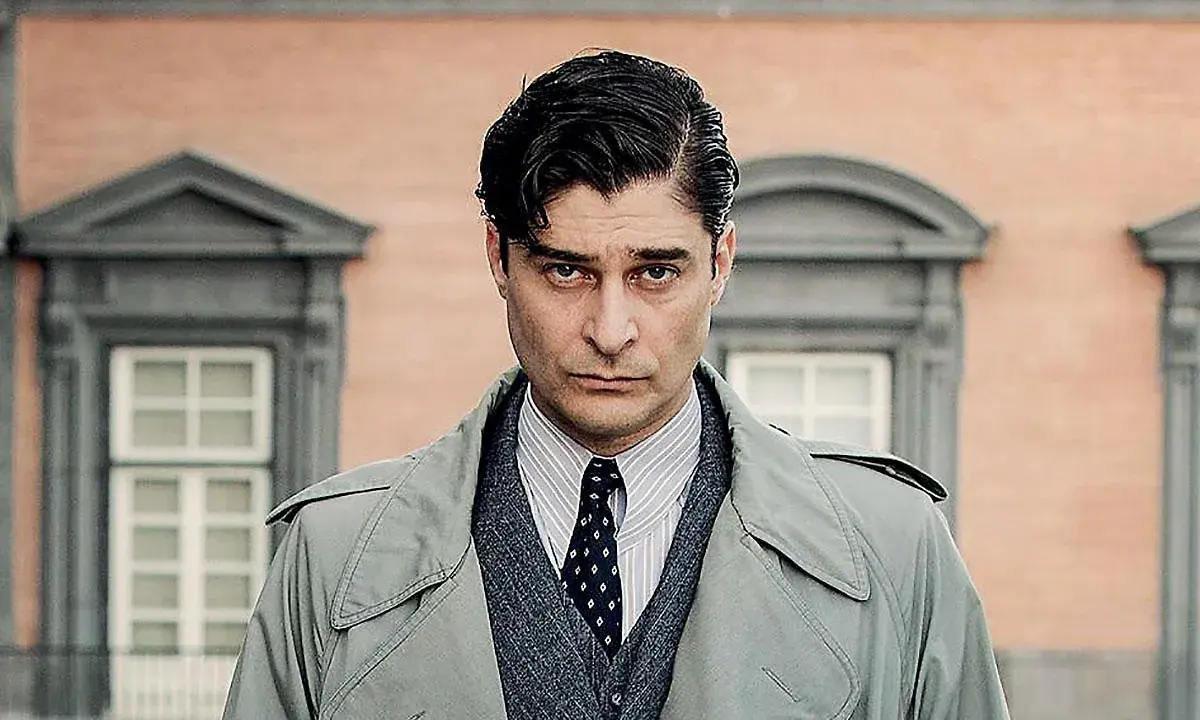 Uomo con trench, camicia a righe e cravatta, con un'espressione seria. Un ritratto creato per mano mia.