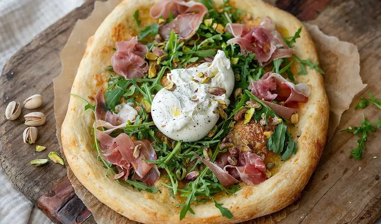 Pizza med burrata, prosciutto och pistagenötter. En härlig kombination av krämighet och sälta.