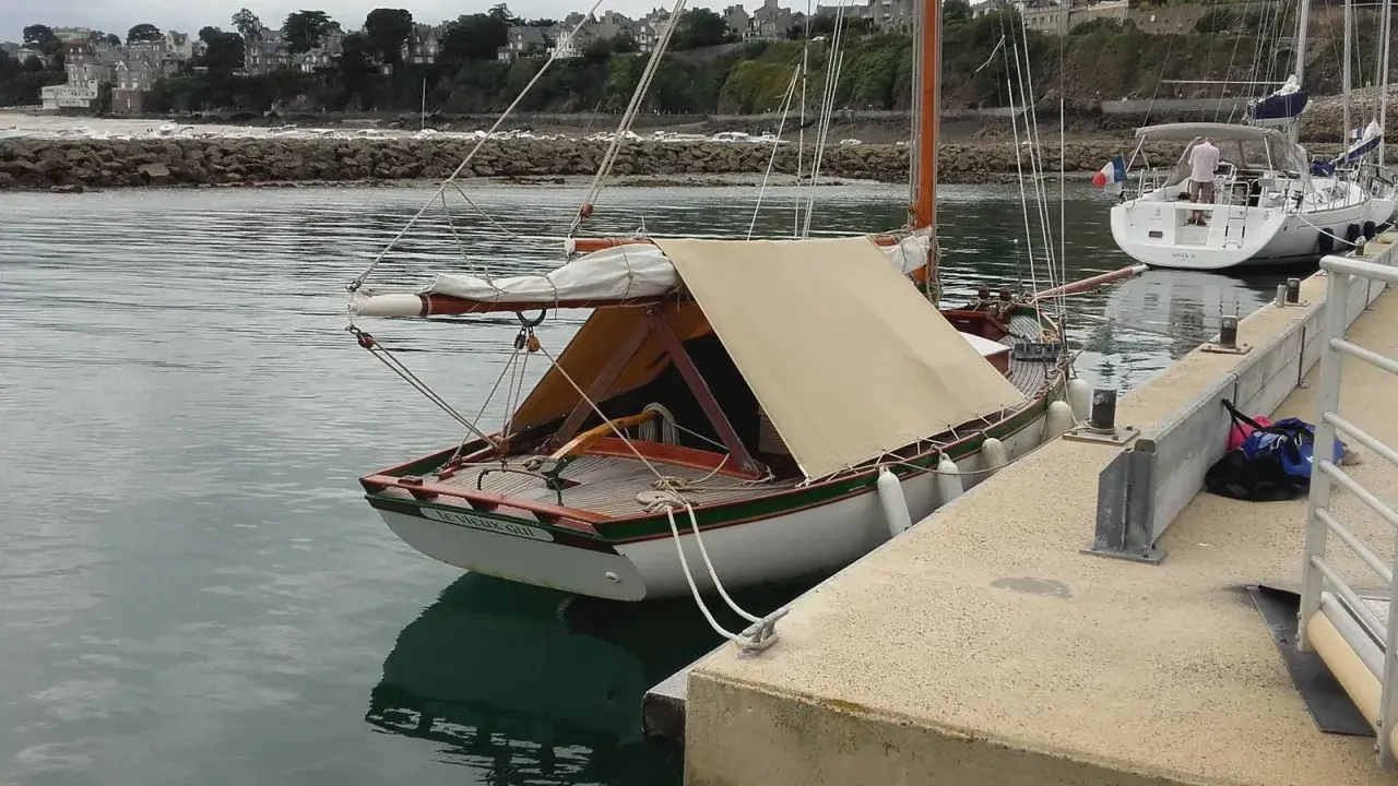 Un cotre de Carantec, "Le Vieux Gui", est amarré au port. Une autre voile blanche est visible à côté.