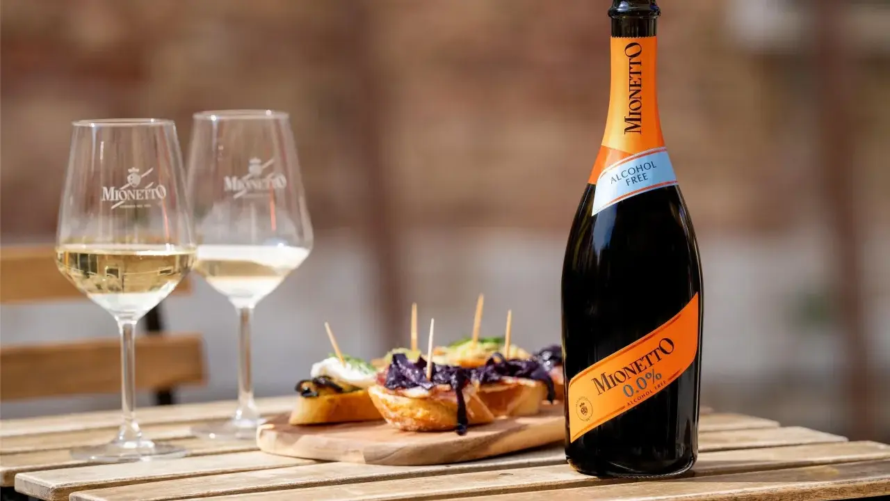 Mionetto alkoholfreier Aperol 0.0% mit zwei Gläsern und leckeren Bruschettas auf einem Holztisch.