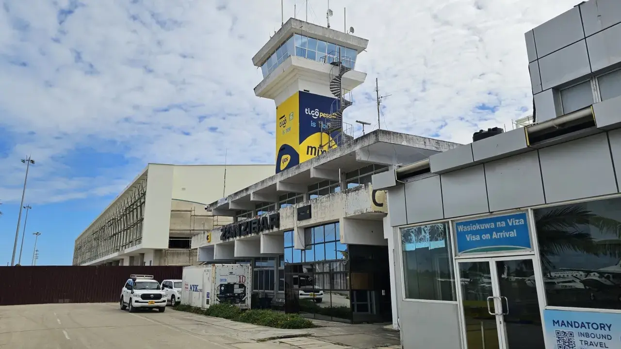 Kontrolltorn och terminalbyggnad vid Zanzibar flygplats. En vit SUV parkerad framför.