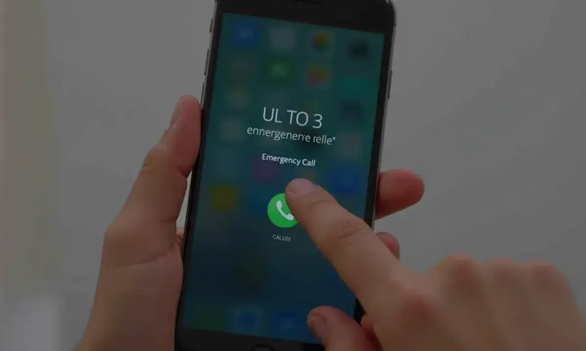 Dłoń naciska przycisk "Emergency Call" na ekranie telefonu, pokazując, jak odblokować telefon przez połączenie alarmowe.
