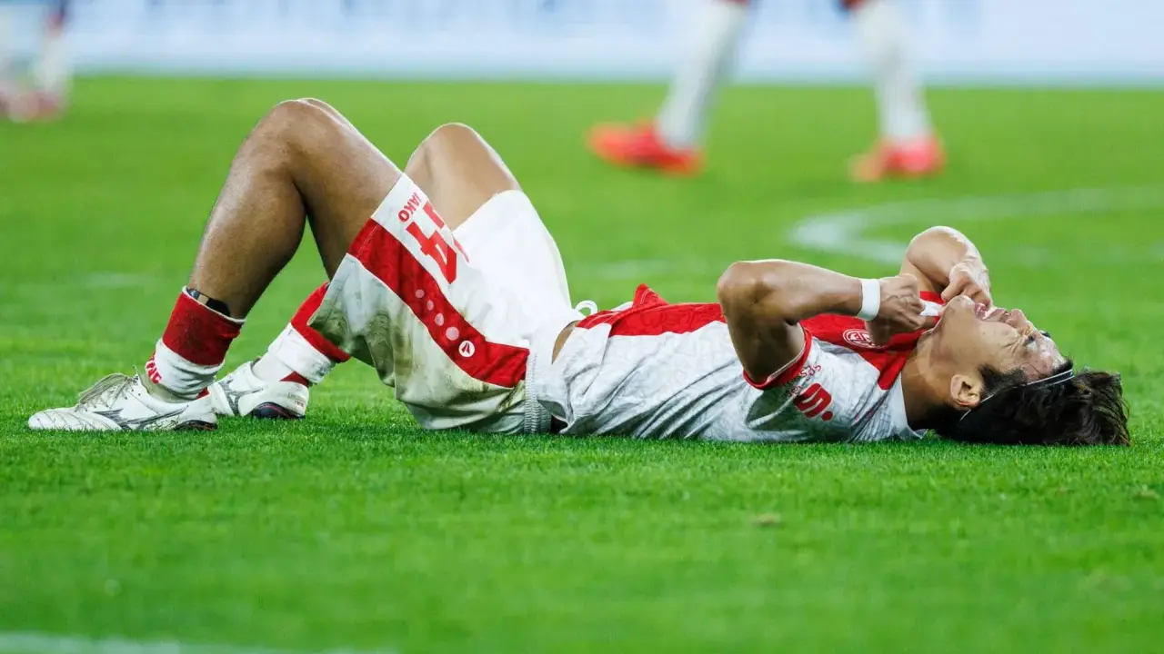 Fußballer liegt erschöpft auf dem Rasen, die Hände im Gesicht. Nach einem harten Spiel braucht er Regeneration.
