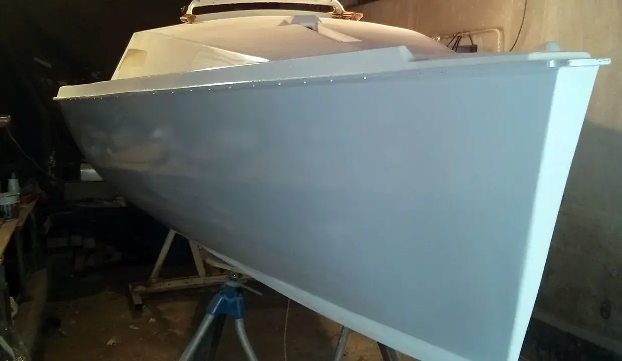 Le bateau Neptune 550, prêt pour sa nouvelle peinture, repose sur des supports dans un atelier.