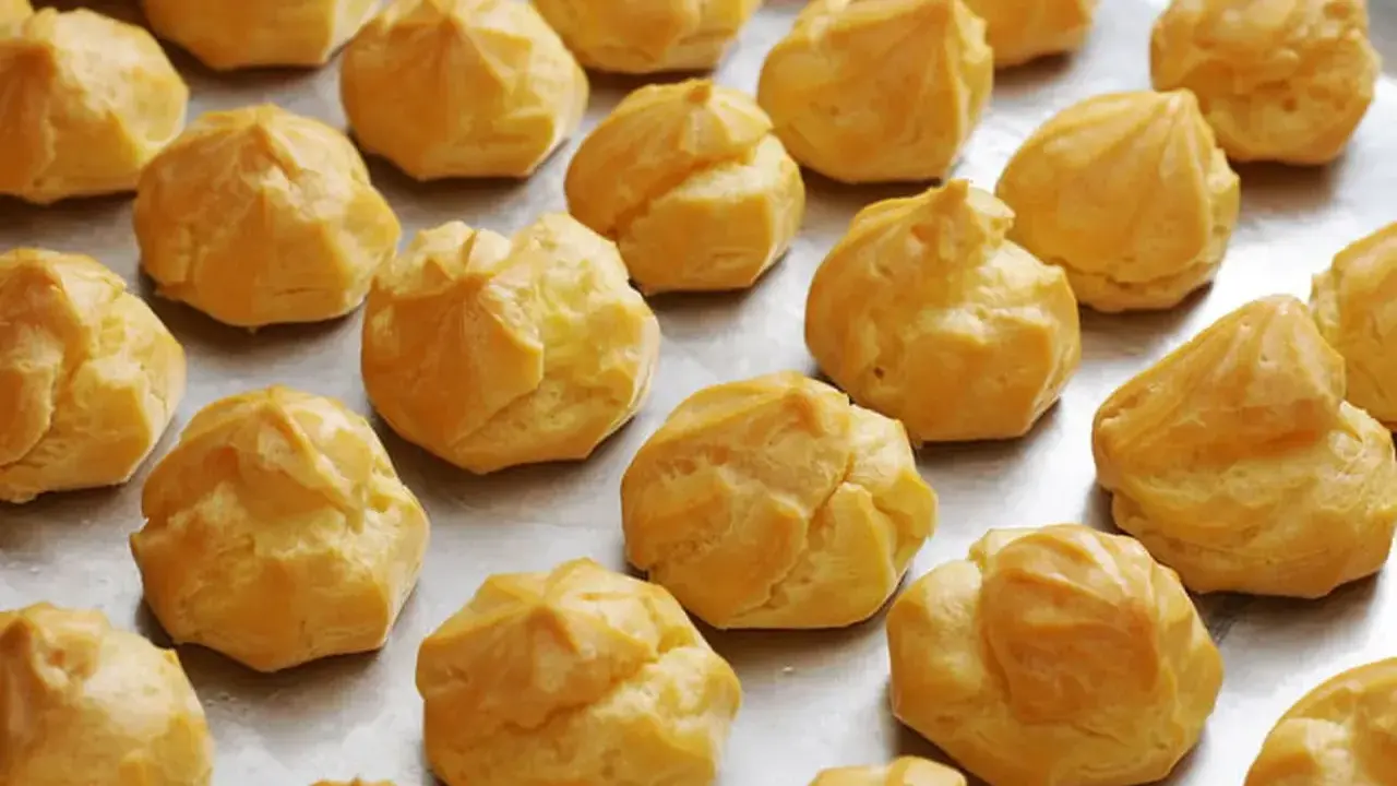 Une fournée de choux à la crème dorés, prêts pour la cuisson. Ils attendent patiemment d'être transformés en délices.