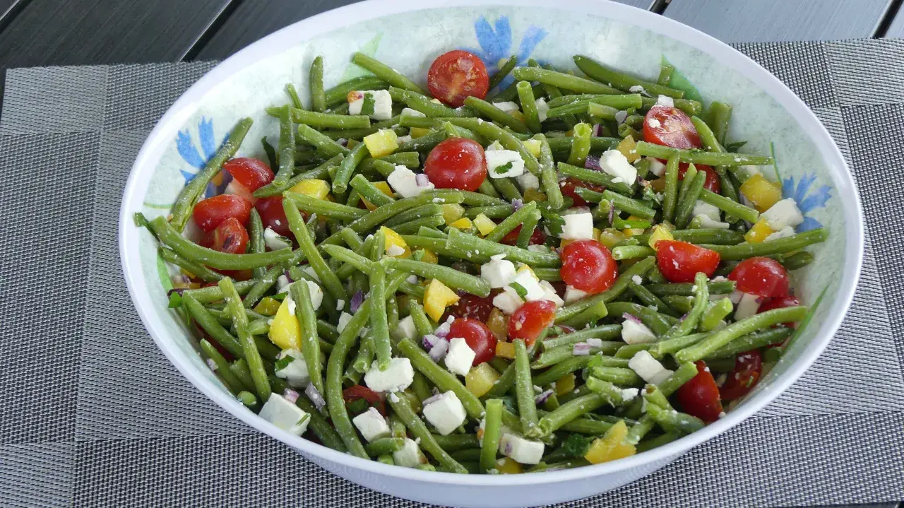 Salade estivale de haricots verts, tomates cerises, poivrons jaunes et feta. Un délice frais et coloré.