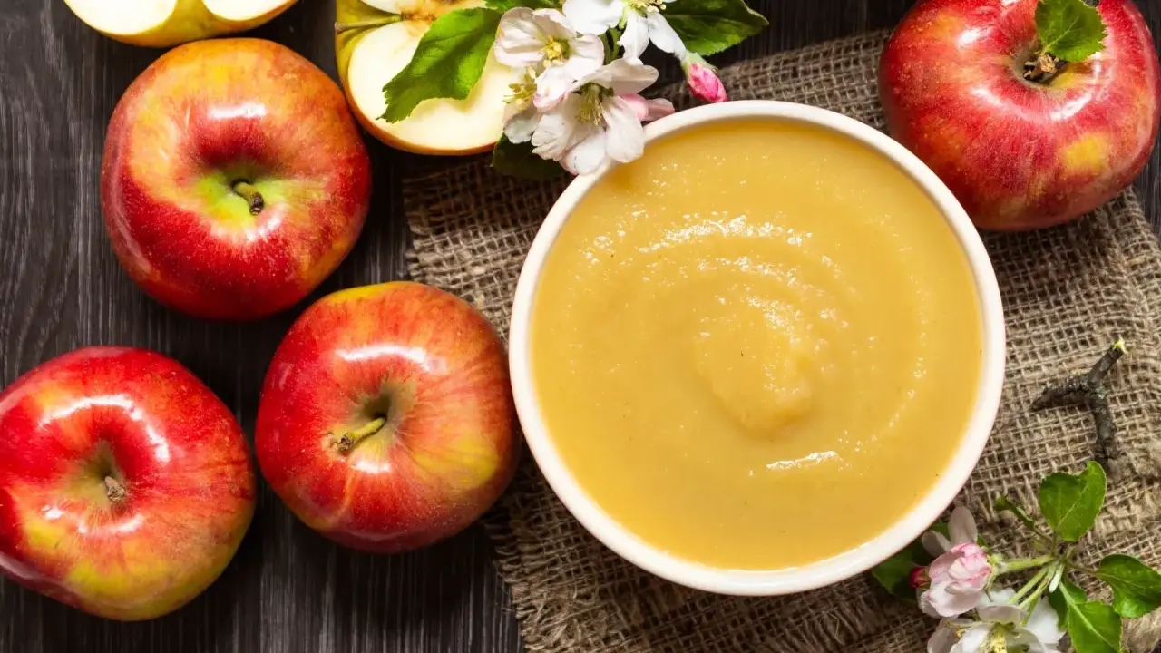 Frische Äpfel und eine Schüssel mit selbstgemachtem Apfelmus, garniert mit Apfelblüten. Ein Genuss für alle Sinne!
