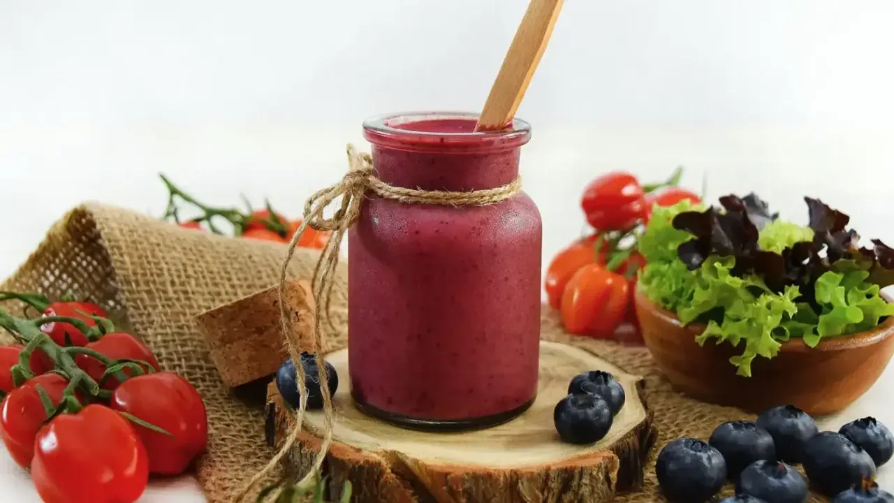 Ein Glas Smoothie, umgeben von frischen Tomaten und Heidelbeeren, die zum Stopfen einladen.