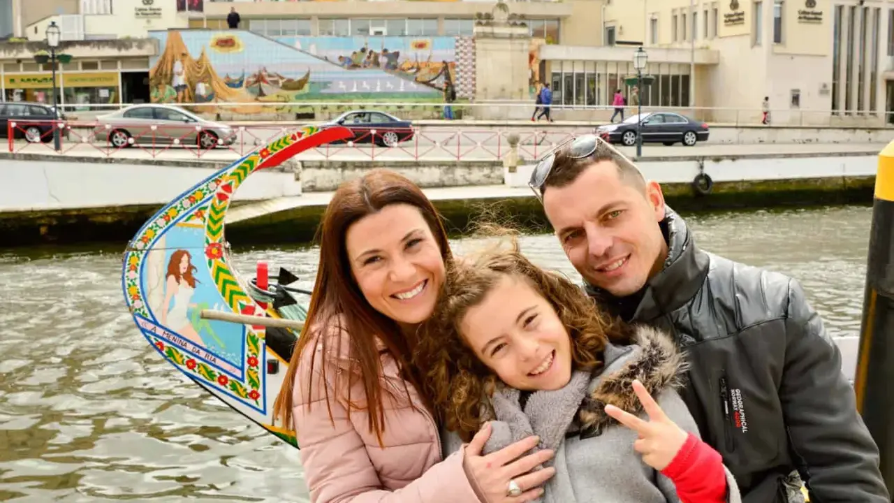 Familia feliz disfrutando de un paseo en góndola en Aveiro con niños. La niña hace el signo de la paz.