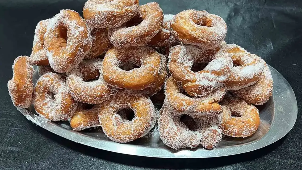 Montón de buñuelos de cuaresma espolvoreados con azúcar, listos para disfrutar.
