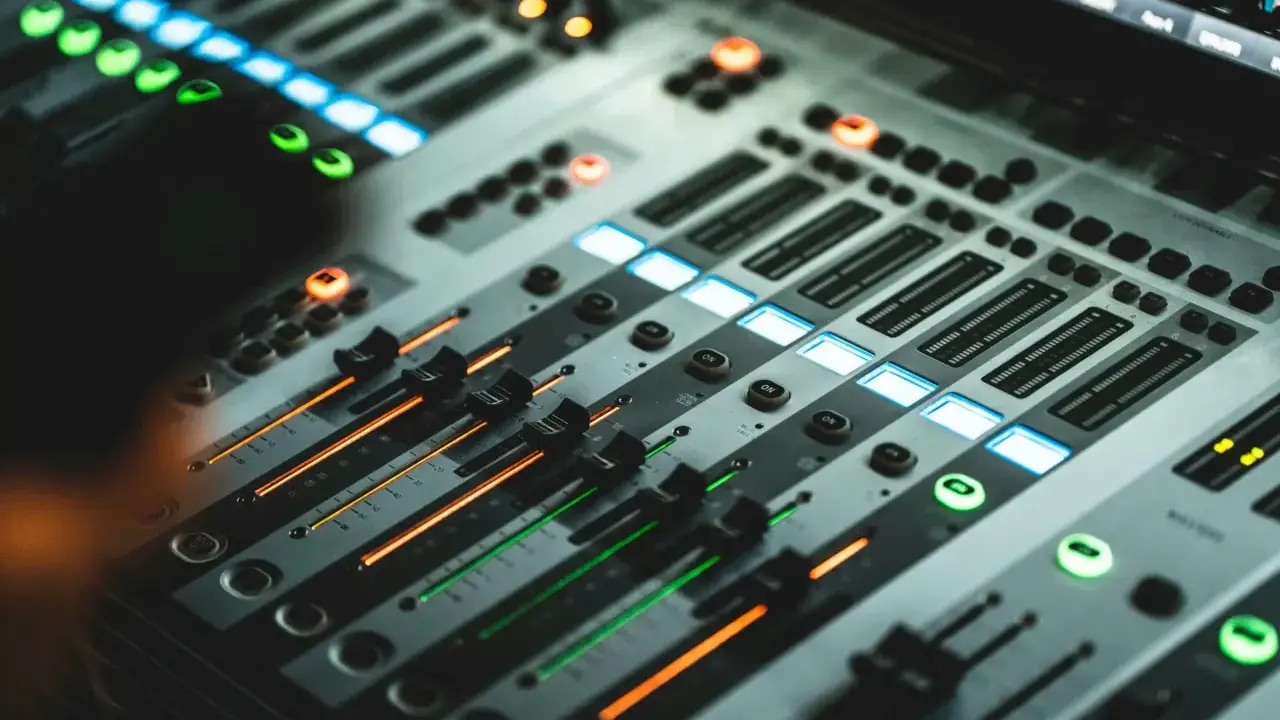 Console de mixage illuminée, prête pour le studio, le mixage et le mastering. Des faders et des boutons lumineux créent une ambiance professionnelle.