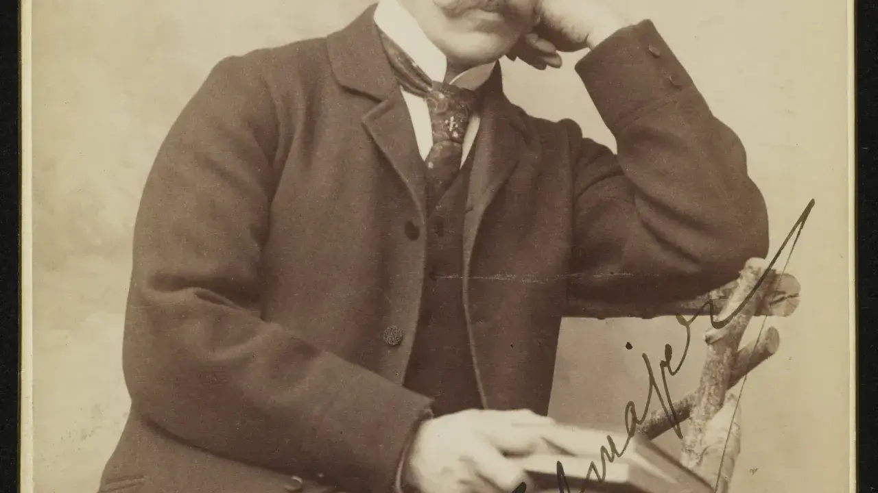 Portret eleganckiego mężczyzny z wąsami, w garniturze i z książką. Może to być znany poeta.