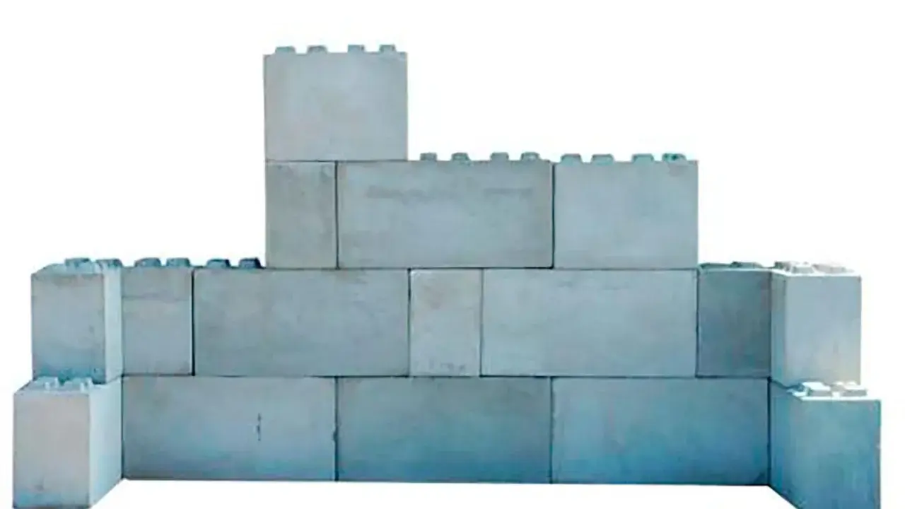 Una pared de bloques grises, apilados de forma irregular, simula un castillo de juguete.