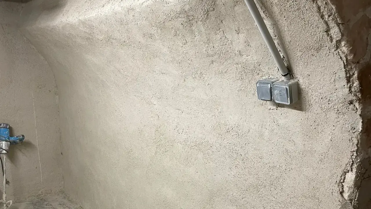 Murs bruts avec prises électriques et tuyauterie, étape clé pour savoir comment assainir une maison.