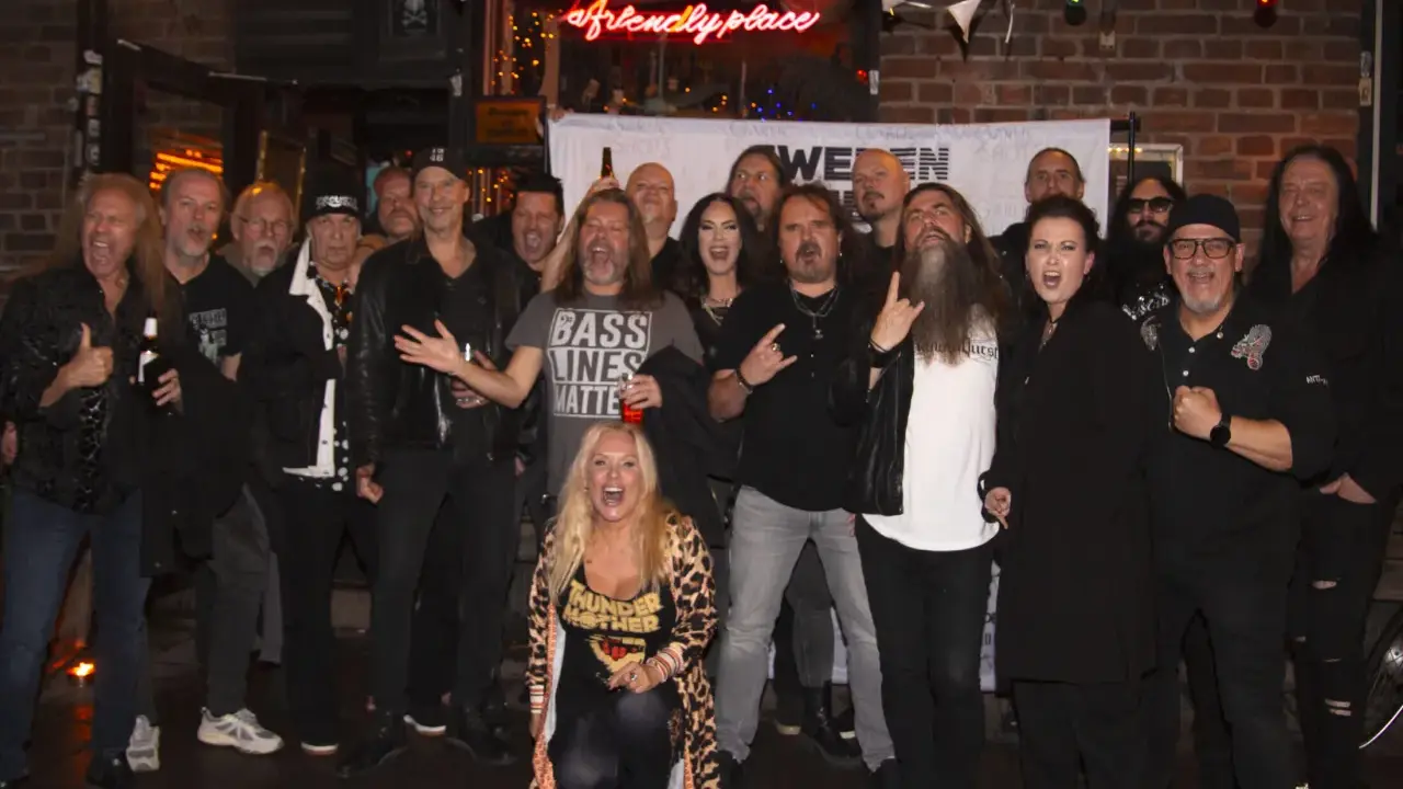 En grupp glada musiker, redo för swedish metal aid. En kvinna i leopardmönstrat poserar i förgrunden.