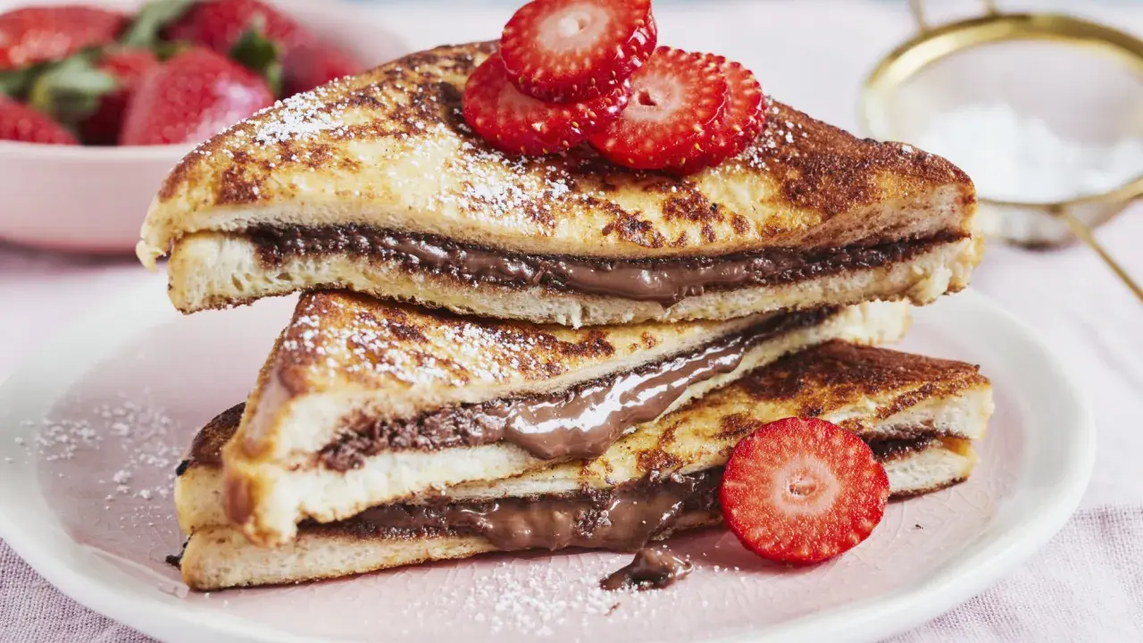 Gestapelte French Toast mit Nutella, bestäubt mit Puderzucker und garniert mit Erdbeeren. Ein süßer Genuss!
