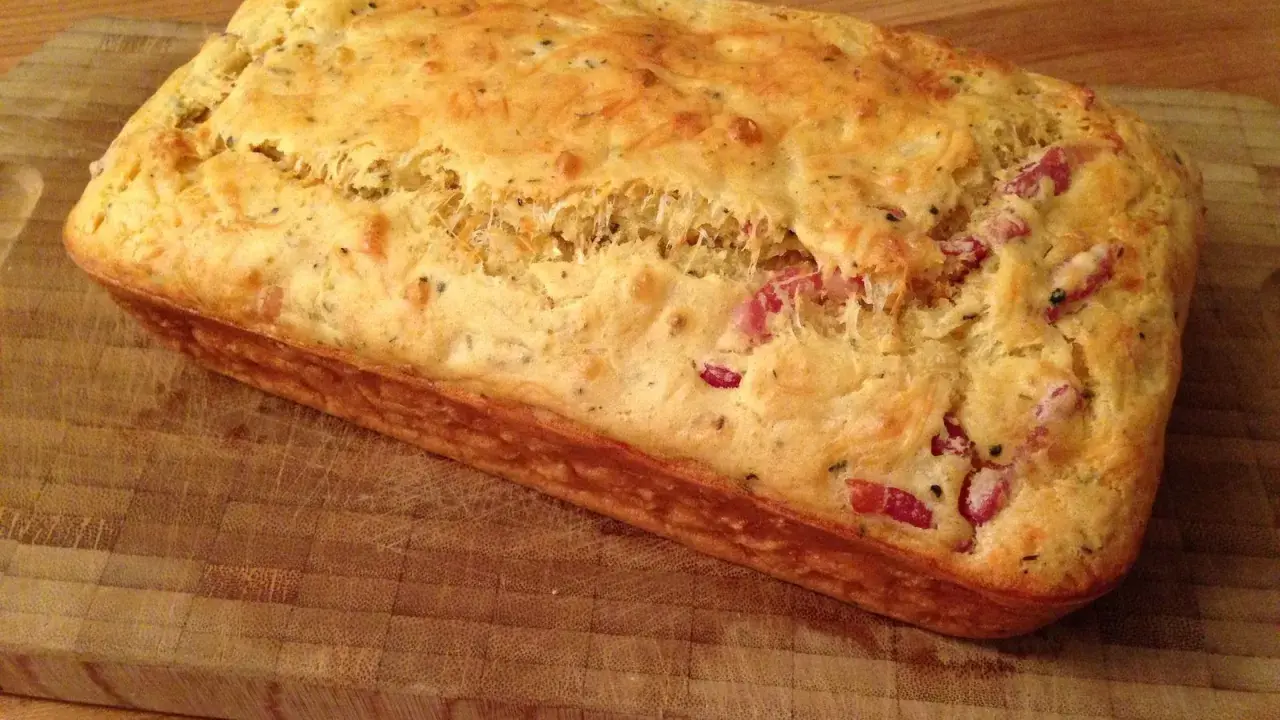 Un délicieux cake aux lardons, doré et moelleux, prêt à être dégusté sur une planche en bois.