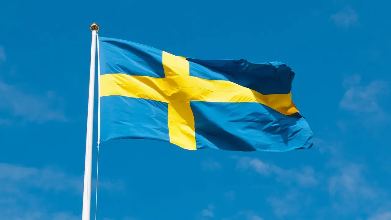 Svenska flaggan vajar i blå himmel. Dess korsdesign har en lång svenska flaggan historia, symboliserande nationens arv.
