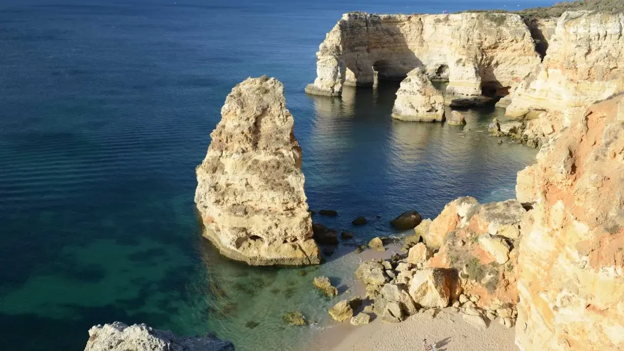 Felsformationen und eine kleine Bucht bei Ilha de Tavira. Das klare Wasser schimmert türkis.