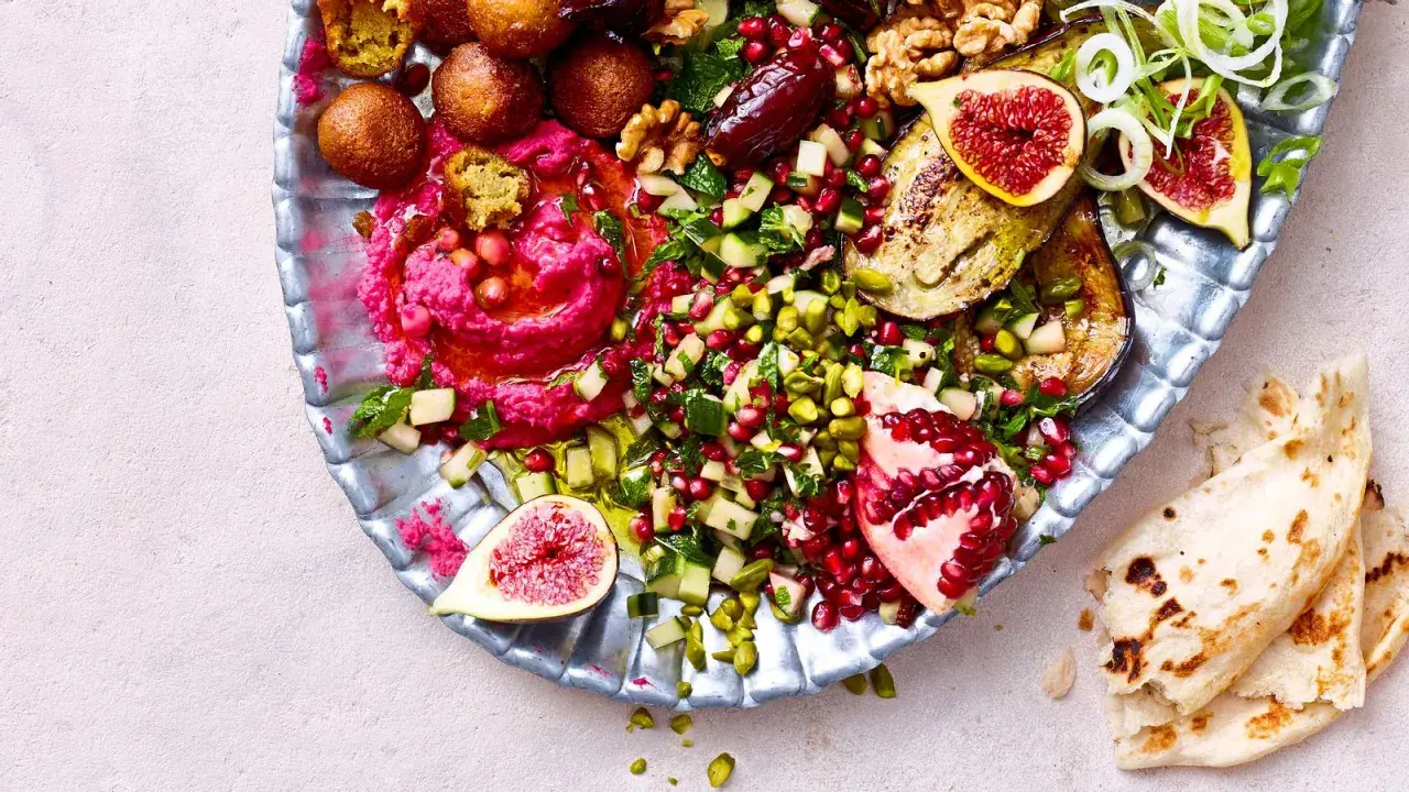 Bunte Mezze-Platte mit Hummus, Falafel, Granatapfel, Feigen und Fladenbrot. Perfekt für ein köstliches Abendessen.