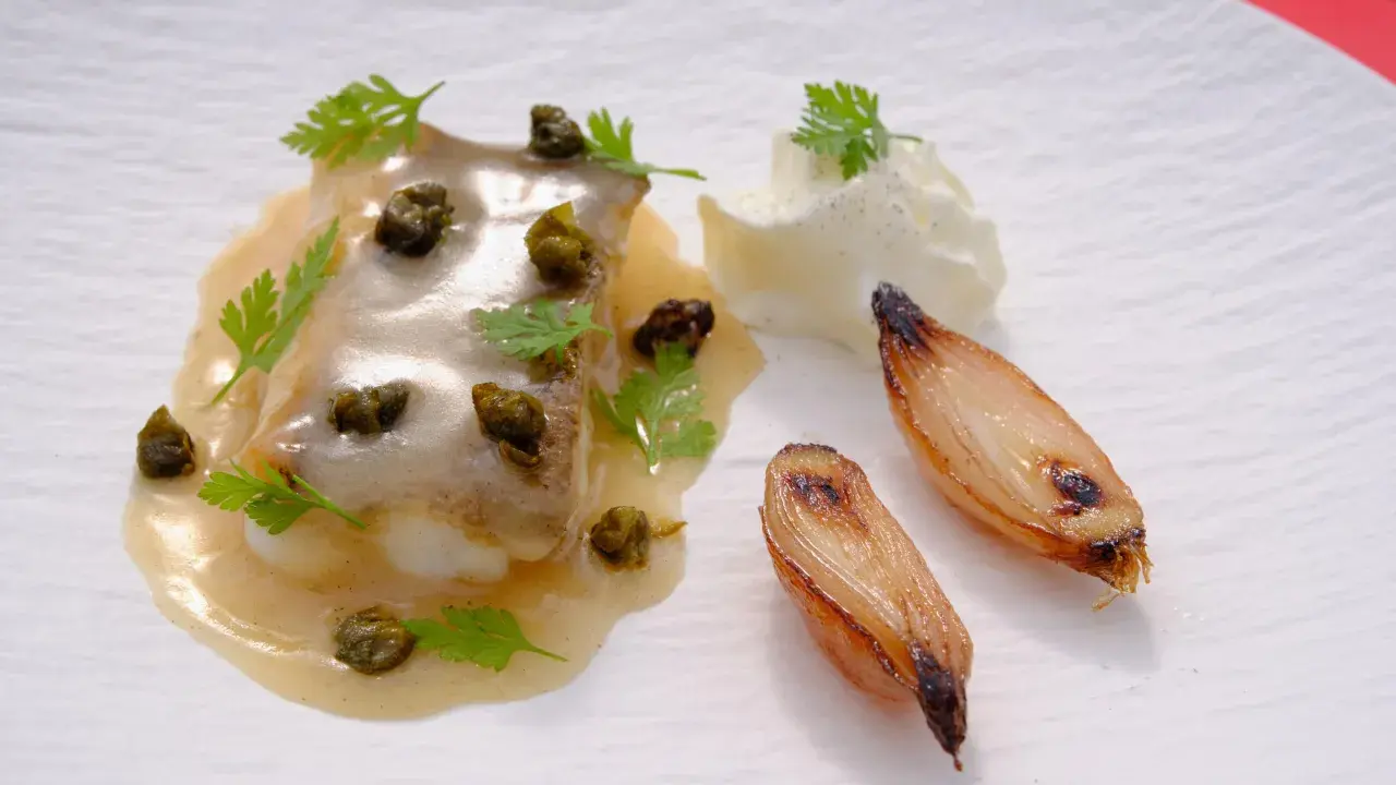 Delicioso lenguado a la meunière con alcaparras, perejil, cebollas caramelizadas y una quenelle de crema.