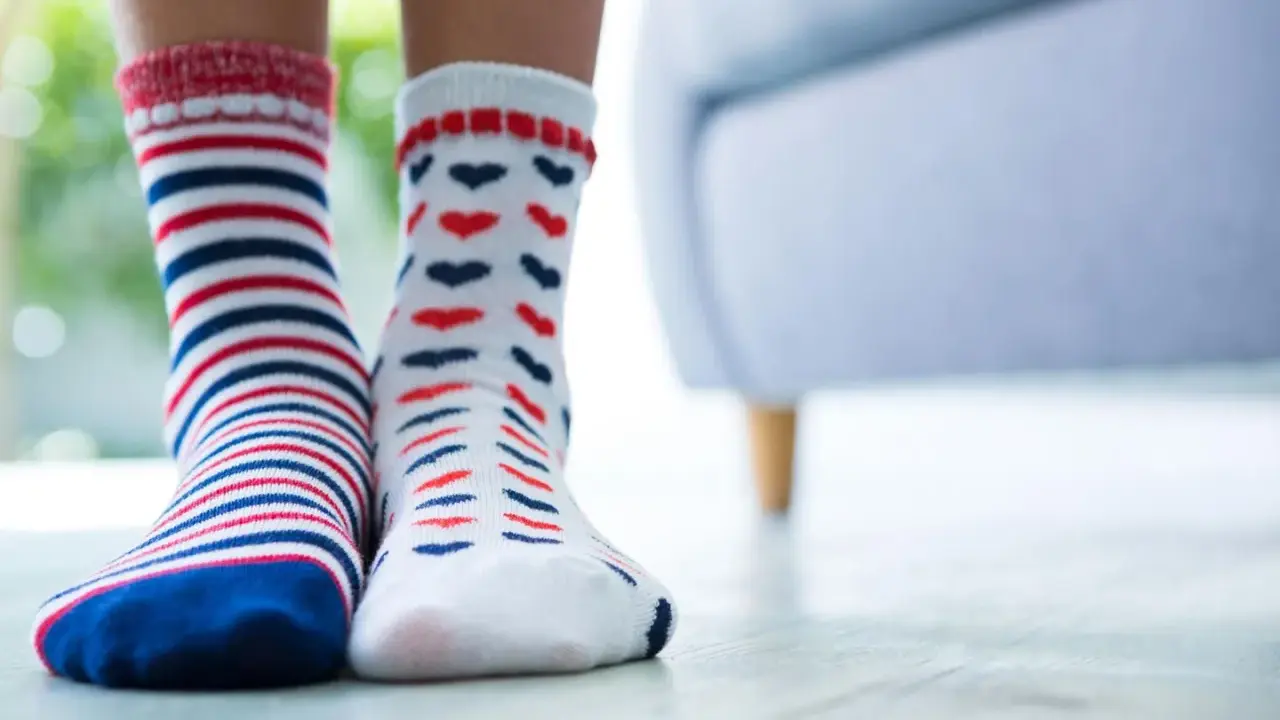 Zwei Paar bunte Socken, gestreift und mit Herzen, warten darauf, mit der richtigen Methode socken sauber bekommen zu werden.
