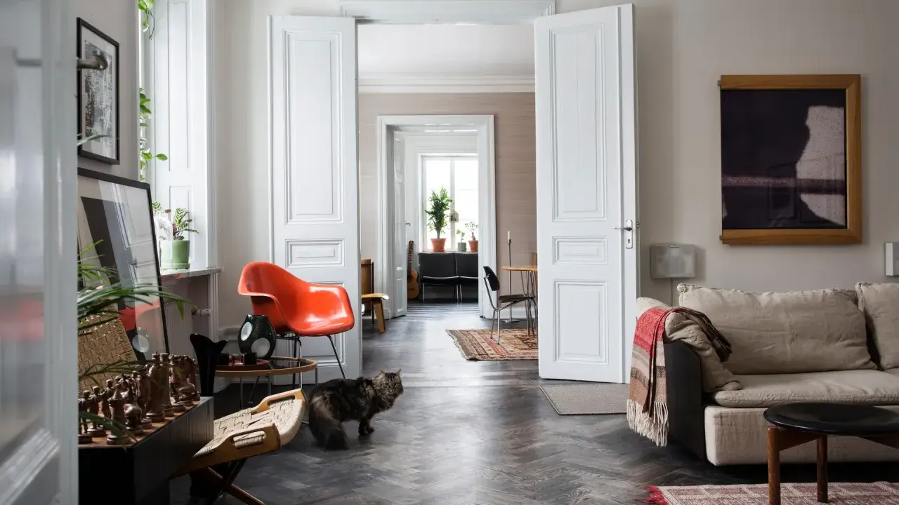 Erika Kangas hem med en katt som smyger förbi en orange stol och en soffa.