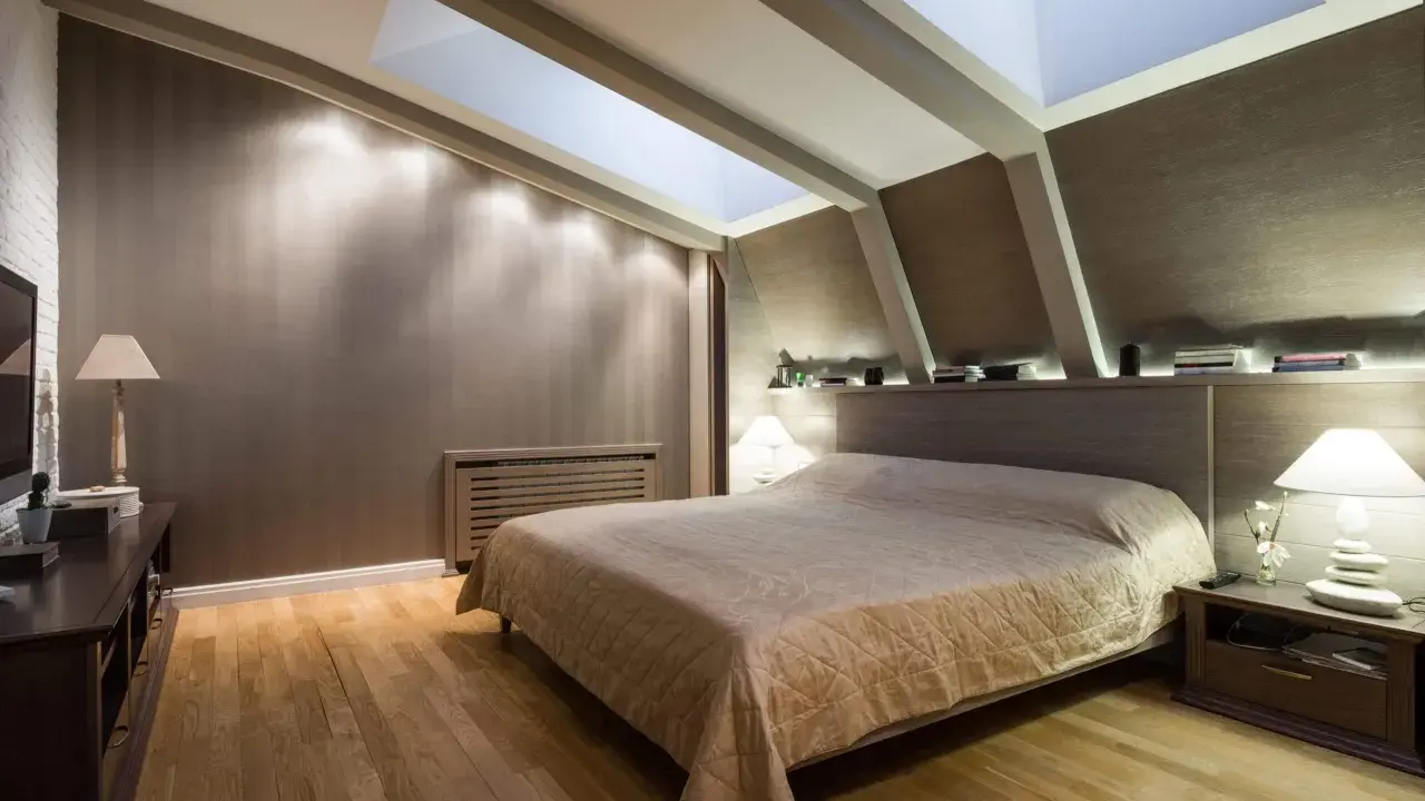 Chambre douillette avec un lit confortable sous une **tête de lit sous pente** et un puits de lumière illuminant la pièce.