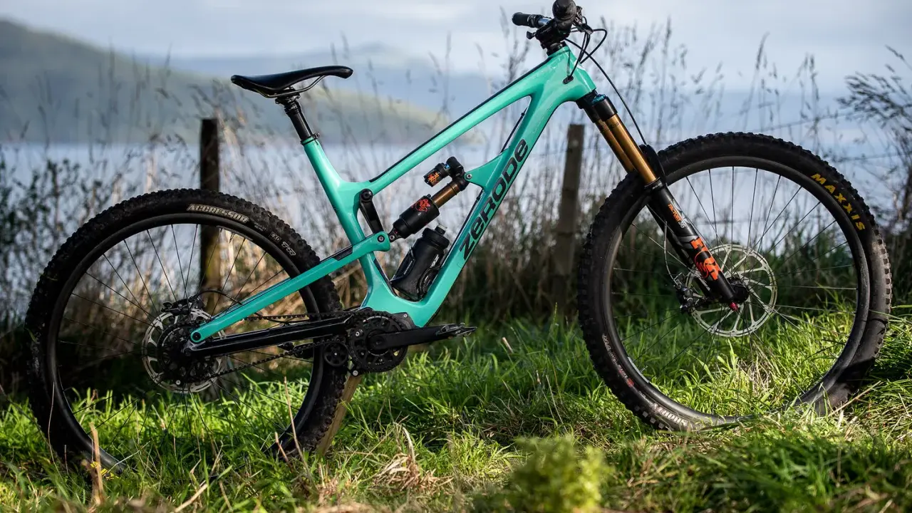 Turkusowy rower full-suspension marki Zerode, gotowy na górskie trasy. Wśród wielu marek rowerów, ten wyróżnia się designem.