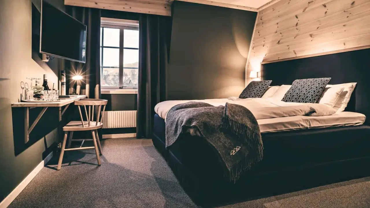 Mysigt rum på vandrarhem i Åre med stor säng, TV och fönster med utsikt.