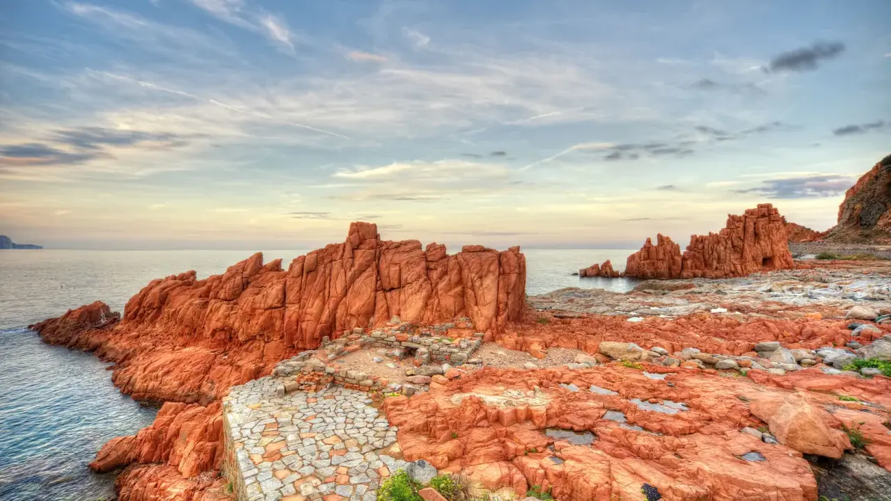 Scogliere rosse e sentiero in pietra a picco sul mare. Un luogo suggestivo da scoprire: Arbatax cosa vedere.