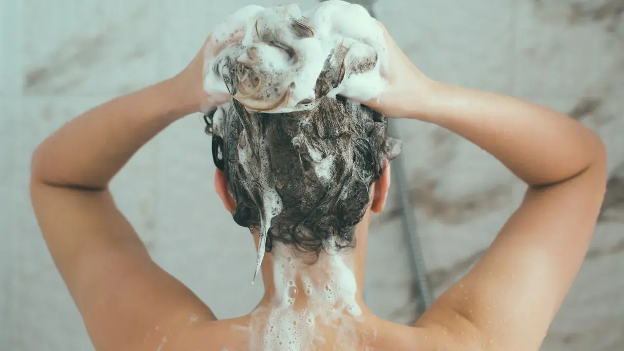 Person wäscht sich die Haare mit schaumbildendem Shampoo. Die Stiftung Warentest hat Olaplex-Produkte untersucht.