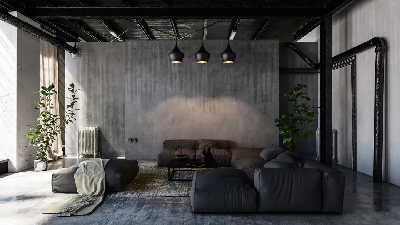 Nowoczesny salon w stylu industrialnym i loftowym. Betonowe ściany, czarne lampy, wygodna, szara sofa i rośliny tworzą surowy, ale przytulny klimat.