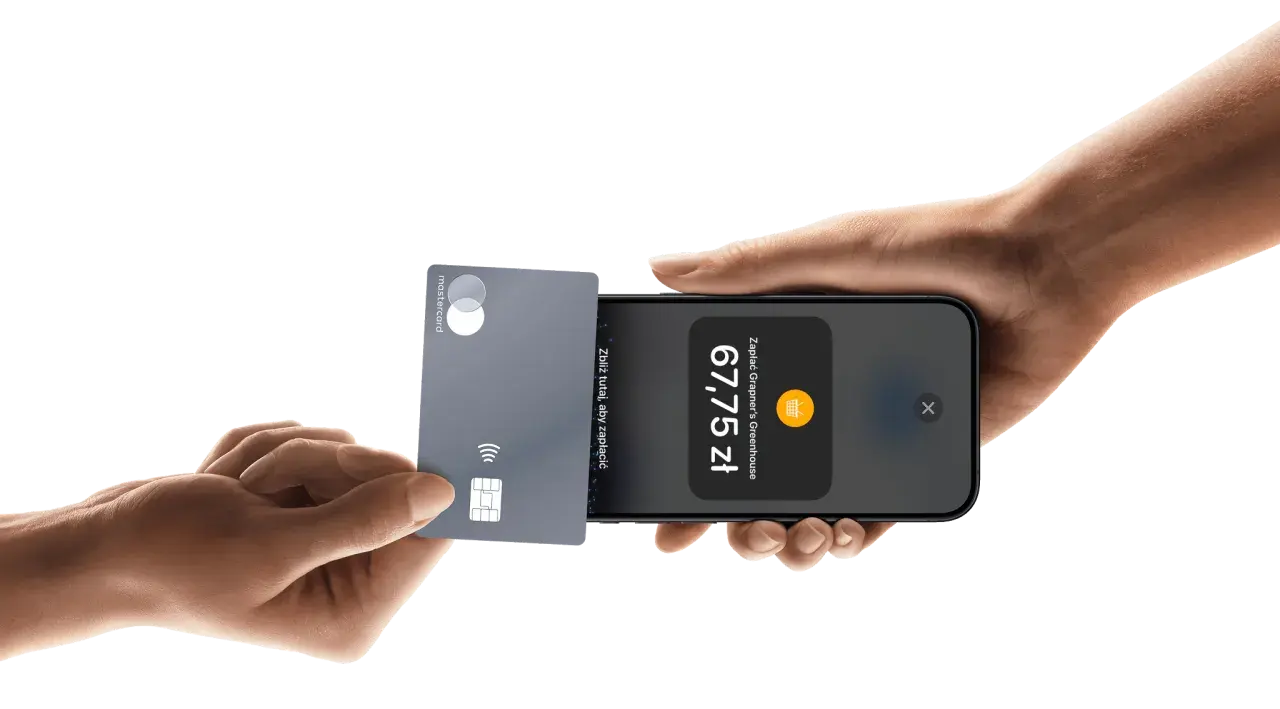 Płatności zbliżeniowe iPhone: karta Mastercard zbliżona do telefonu, wyświetlona kwota 67,75 zł.