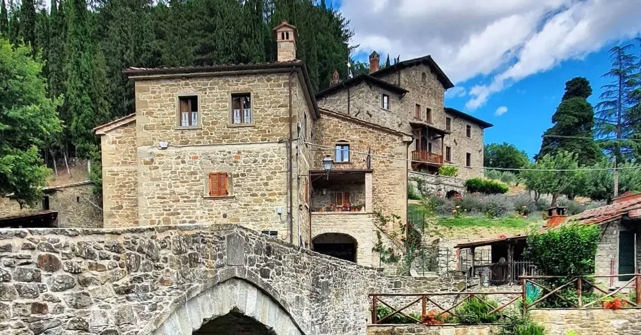 Antico ponte in pietra e case in pietra, tipici dei borghi vicino Arezzo, immersi nel verde della campagna toscana.