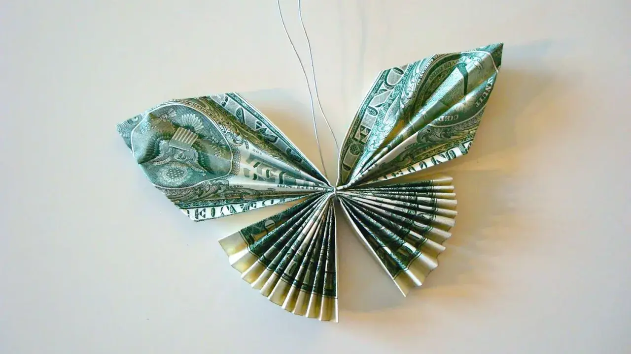 Schmetterling aus gefalteten Geldscheinen, kunstvoll arrangiert. Die feinen Knicke der Geldscheine formen zarte Flügel.