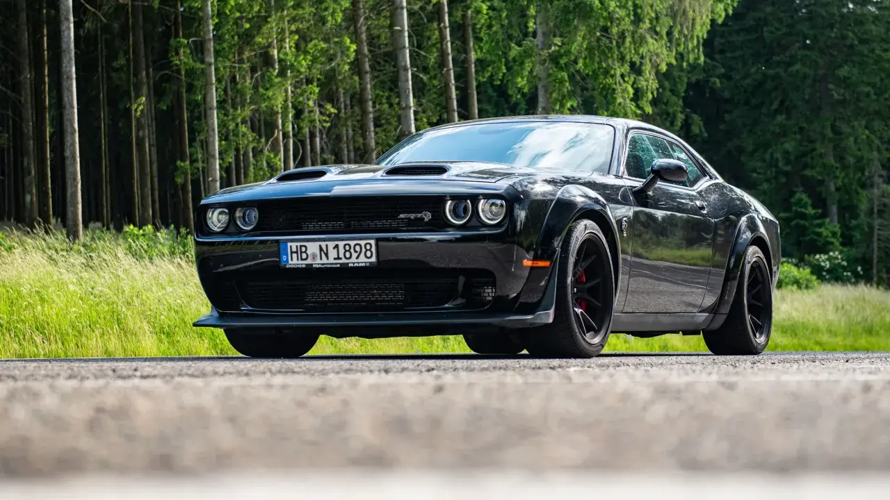 Schwarzer Dodge Challenger SRT Hellcat Redeye parkt am Waldrand.
