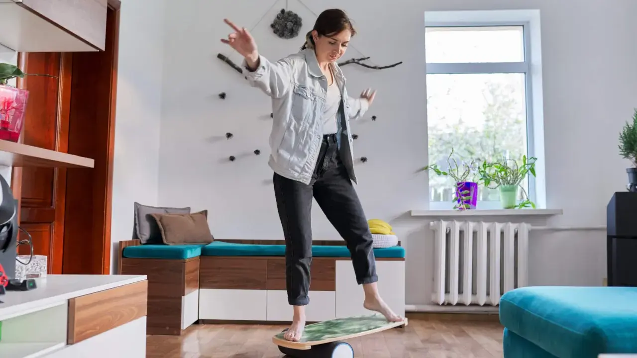 Kvinna balanserar på en balansbräda, en övning som kan hjälpa till med fokus och inre lugn, liknande en hjärtchakra meditation.