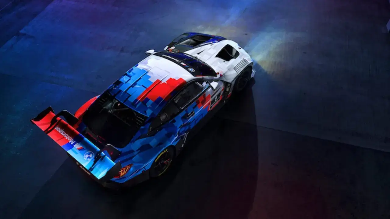 Der BMW M4 GT3 in dynamischer Motorsport-Lackierung steht bereit für die Rennstrecke, beleuchtet von Scheinwerfern.