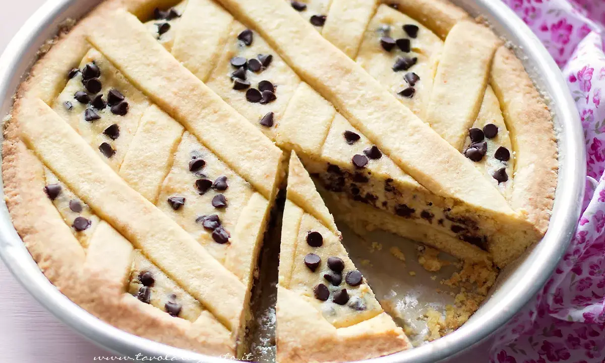 Deliziosa torta ricotta e cioccolato con decorazione a griglia e gocce di cioccolato. Una fetta è stata tolta, rivelando il ripieno cremoso.