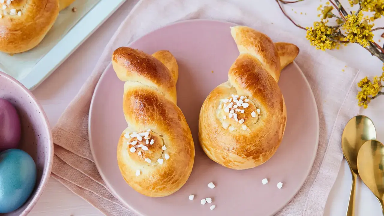Zwei goldbraune Hefehasen mit Zuckerkristallen, bereit zum Osterfrühstück. Das Backen von Hefehasen ist eine schöne Tradition.