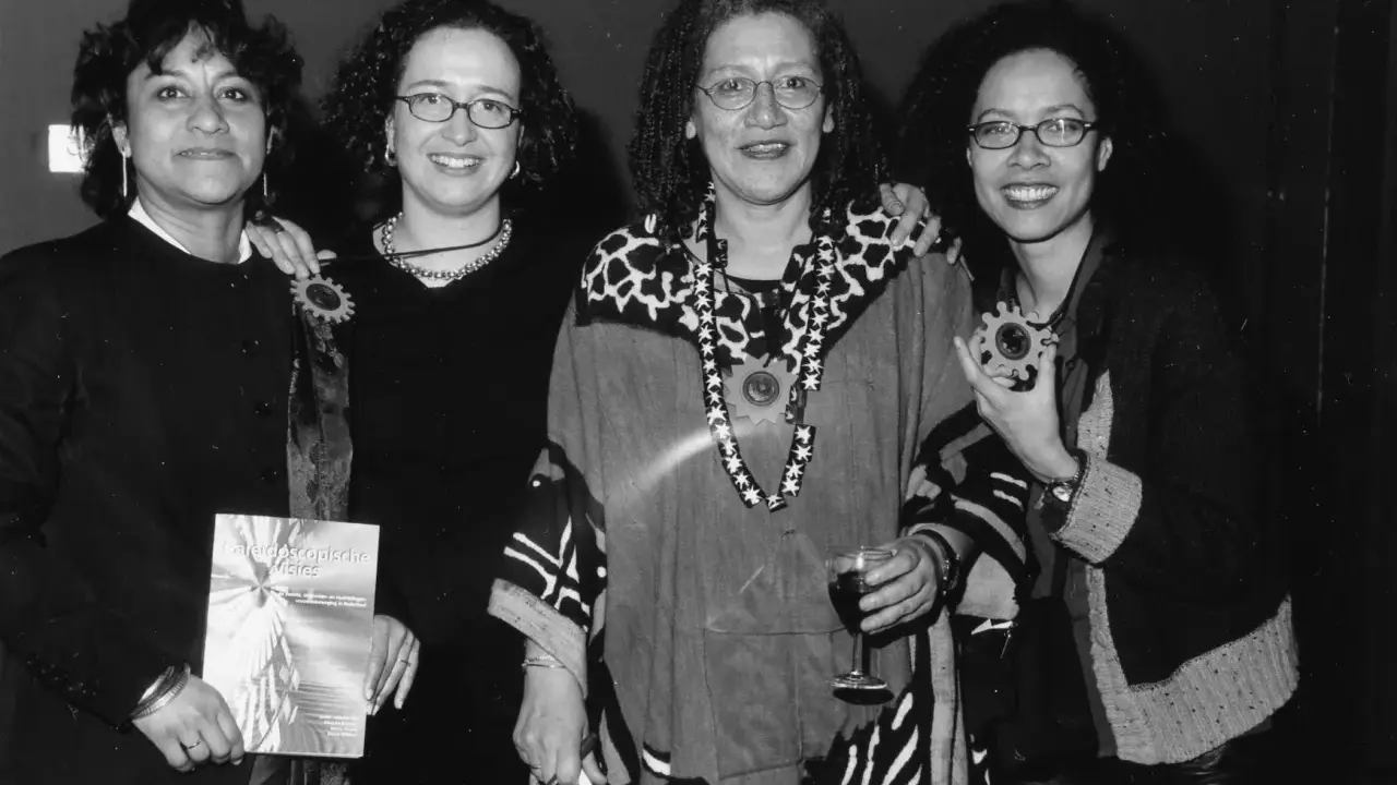Vier vrouwen, symbool voor intersectionaliteit en feminisme, poseren met een boek en een glas wijn.